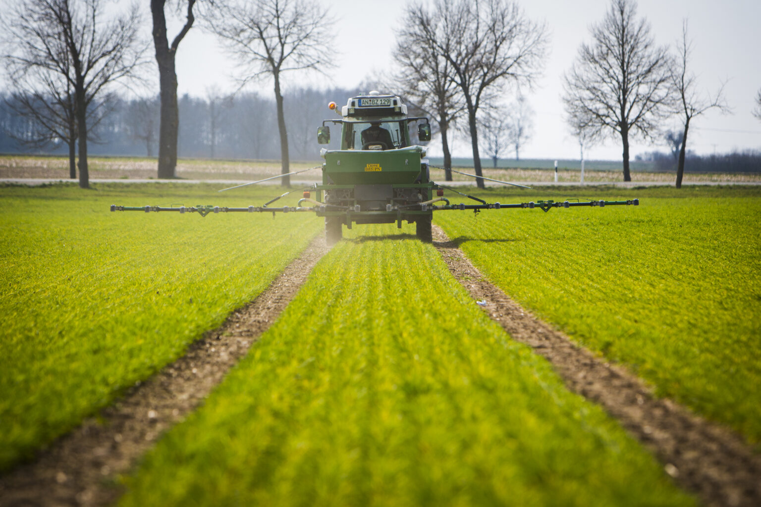 Auf einem Versuchsfeld ist ein Traktor mit einem Pneumatikstreuer ohne ISOBUS bei der teilflächenspezifischen Stickstoff-Düngung zu sehen.