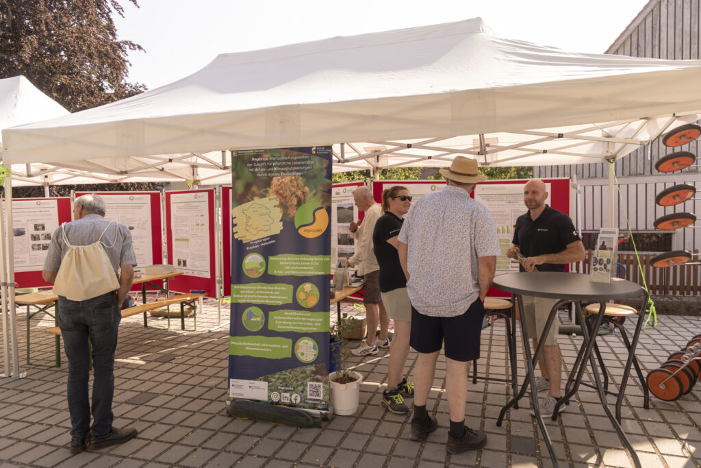 Unser Foto zeigt den Stand des Biomasse-Instituts am Johannitag 2026. Hier die Präsentation des Projekts "regiopakt".