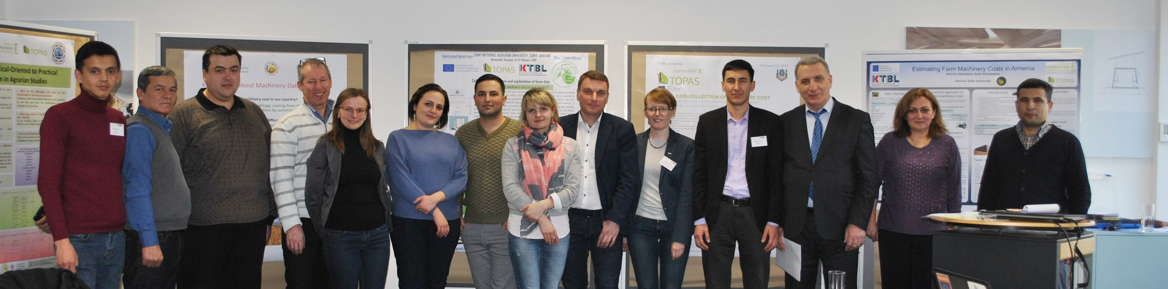 Gruppenbild der 13 Teilnehmer in einem Saal mit Plakaten zwischen ihnen Prof. Schlauderer