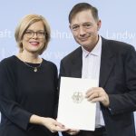 Die beiden Personen halten zusammen den Förderbescheid