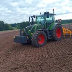 Auf dem Bild ist ein Versuchsschlepper mit einem Bodenbearbeitungsgerät auf einem Acker zu sehen.