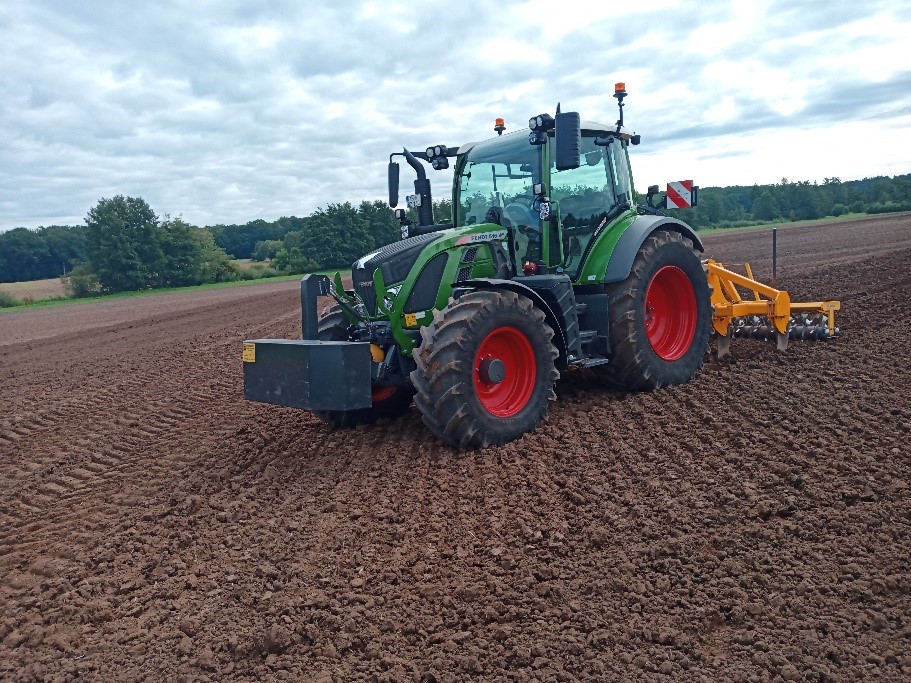 Auf dem Bild ist ein Versuchsschlepper mit einem Bodenbearbeitungsgerät auf einem Acker zu sehen.