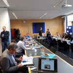 Teilnehmer sitzen an langen Tischen